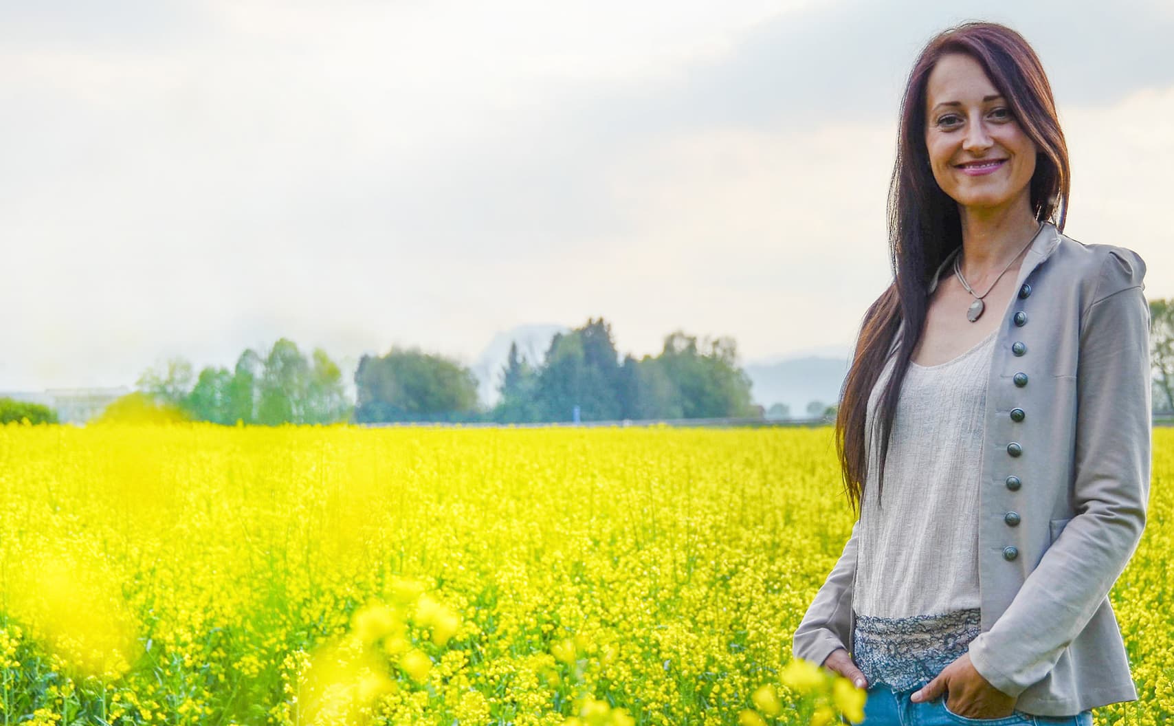 Nicole Künzl steht lächelnd vor einem blühenden Rapsfeld