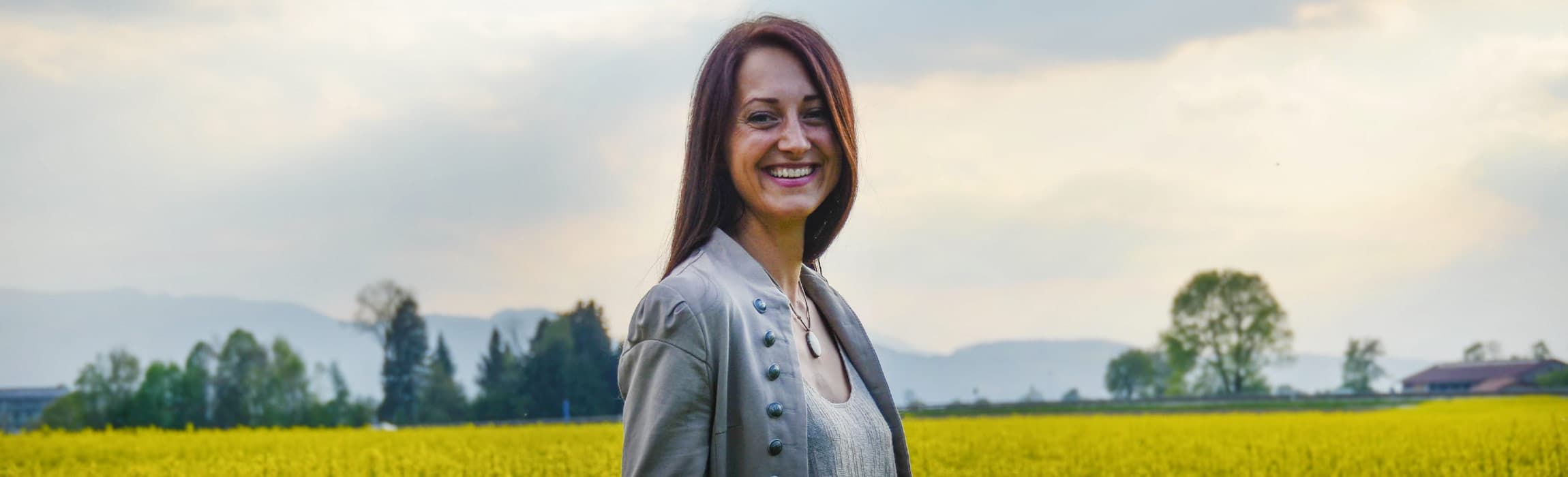 Nicole Künzl steht lächelnd vor einem blühenden Rapsfeld