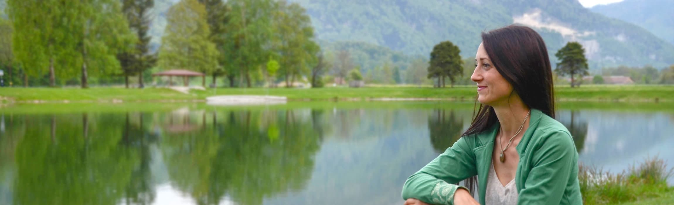Nicole Künzl sitzt an einem See und blickt in die Ferne